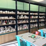 Shelves filled with ceramic figurines and pottery in a bright, modern display area.