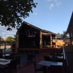 Outdoor stage and seating area at a venue under a clear blue sky.