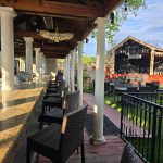 Outdoor patio with bar, seating area, and view of a rustic barn under a bright sky.