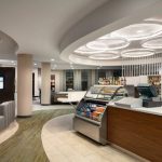 Modern hotel lobby with reception desk, seating area, and ambient lighting.