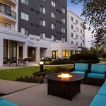 Modern apartment complex exterior with outdoor seating area and fire pit at dusk.