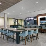 Modern communal area with large table, seating, and a sleek bar counter.
