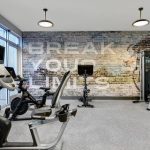 Gym interior with treadmills and bikes against a distressed brick wall mural.