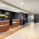 Modern hotel lobby with a sleek reception desk and light wood flooring.