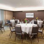Conference room setup with round tables, chairs, and a Courtyard by Marriott sign.