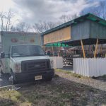 Green roadside stand advertising Cuban and Puerto Rican food, with a truck parked nearby.