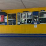Bright yellow ice cream shop with multiple windows and signs under a covered awning.