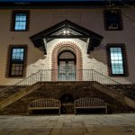 Historic building facade at night with a central arched entrance and stone steps.