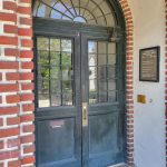 Dark wooden double doors with glass panels under a brick archway.