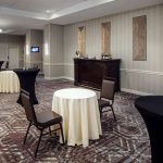 Conference room setup with round tables, chairs, and a serving station.