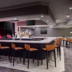 Modern bar area with a sleek counter, seating, and dining tables in a contemporary interior.