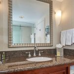 Bathroom vanity with granite countertop, large mirror, and modern fixtures.