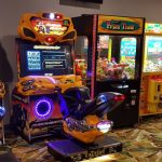 Arcade game machines lined up in a dimly lit entertainment area.