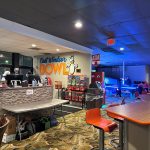 Bowling alley interior with lanes, a front desk area, and colorful lighting.