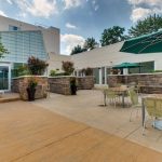 Outdoor patio area with dining tables, lounge space, and modern building backdrop.