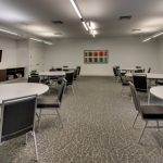 Conference room with white tables, chairs, and modern lighting fixtures.