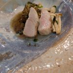 Sliced pink meat with herbs and mushrooms on a rustic blue and white plate.