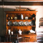 Wooden hutch display in a rustic kitchen setting with dishes and pottery.