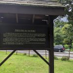 Historical marker detailing "Prelude to Victory" beside a road with trees in the background.