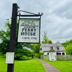 Historic sign for Johnson Ferry House, circa 1740, near a white farmhouse.