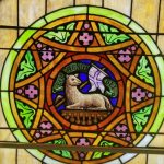 Stained glass window featuring a central medallion with a wolf and a purple banner.