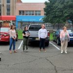 Group of students gathered outdoors in a parking lot, listening to a speaker.