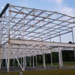Steel framework structure under construction against a clear blue sky.