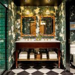 Ornate bathroom with dark wood vanity, gold mirrors, and green patterned wallpaper.