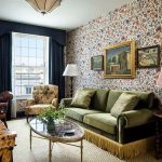 Elegant living room with patterned wallpaper, green sofa, and antique decor.