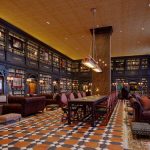 Ornate library lounge with dark wood shelves, leather seating, and a checkered tile floor.