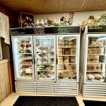 Refrigerated display case stocked with meats, cheeses, and prepared foods in a deli setting.