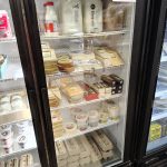 Dairy products, including milk and cheese, displayed in a refrigerated glass-door freezer case.