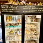 Refrigerated display case stocked with farm fresh eggs, cheeses, yogurt, and gourmet items.