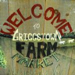 Welcome to Griggstown Farm Market sign with rustic wood background and farm scene.