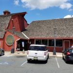 Red barn and building with "Halo Farm" sign, parking lot in front under blue sky.