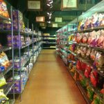 Grocery store aisle with tall shelves stocked with various food products.