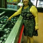 Woman standing next to a refrigerated display case in a store aisle.