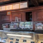 Ice cream display case with tubs, menu board above a rustic wooden bar.