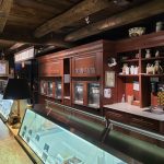 Rustic interior with wooden shelving displaying goods and a glass display case.