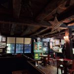 Rustic interior of a dimly lit bar with exposed wooden beams and vintage decor.