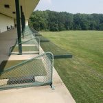 Bleachers overlooking a large, grassy sports field under a bright sky.