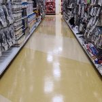 A long, brightly lit aisle in a comic book store with shelves packed with merchandise.