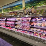 Refrigerated display case filled with various fresh fruits and prepared fruit salads in a grocery store.