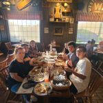 Group of friends dining and socializing in a rustic, warmly lit restaurant interior.