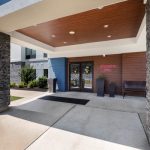 Modern hotel entrance with stone columns, wood ceiling, and Hampton Inn signage.