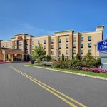 Hampton Inn & Suites hotel exterior with blue signage on a sunny day.