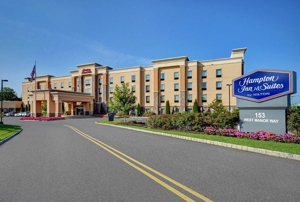 Hampton Inn & Suites hotel exterior with blue signage on a sunny day.