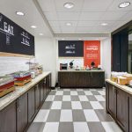 Buffet line with food display, black chalkboard menu, and checkered floor in a modern dining area.