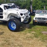 White Jeep Wrangler off-road vehicle parked outdoors at a grassy event.