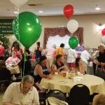 Party celebration with balloons, decorations, and people gathered around tables.